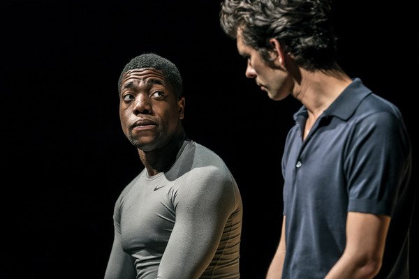 © RADA graduate and actor Fehinit Balogun sits on stage in conversation with Ben Whishaw in a scene from Against at the Almeida Theatre Johan Persson